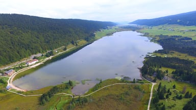 A large lake surrounded by forested hills and a few buildings.