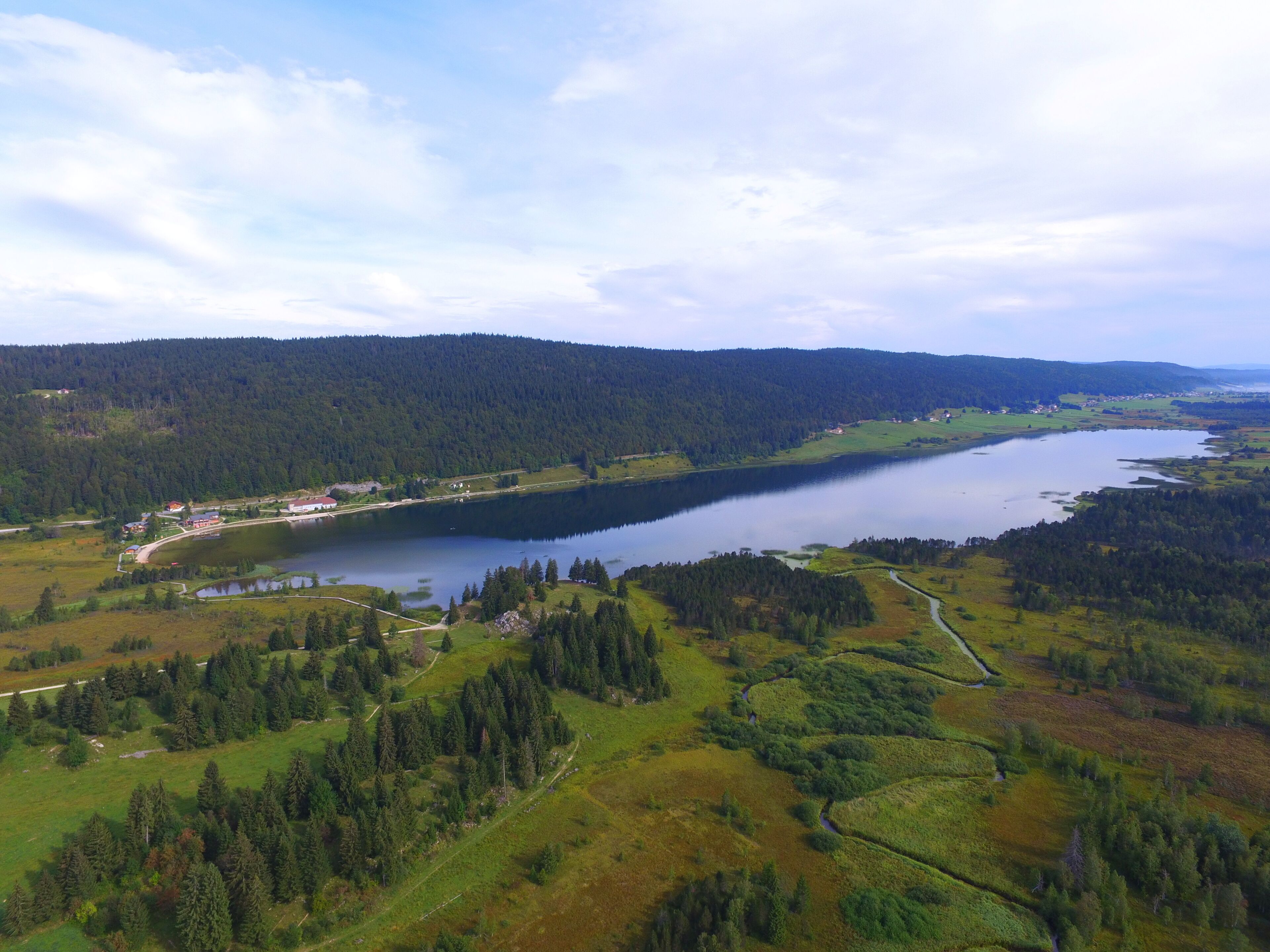 A lake surrounded by forested hills and a small village.