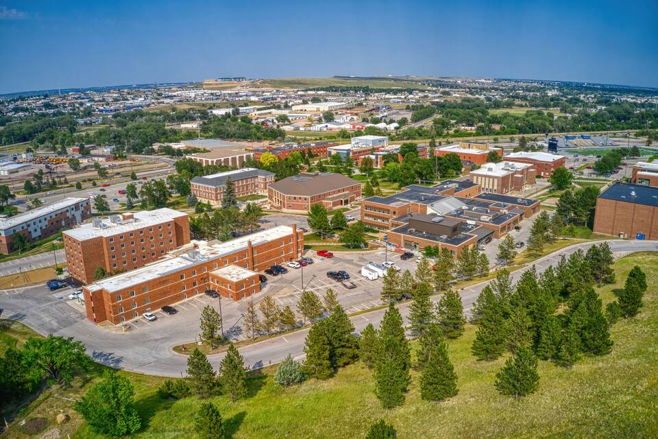 Vue aérienne d’un campus comprenant plusieurs bâtiments, des parkings et de nombreux espaces verts.