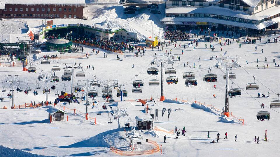 A snowy ski resort with multiple ski lifts, a ski area, and buildings in the background.