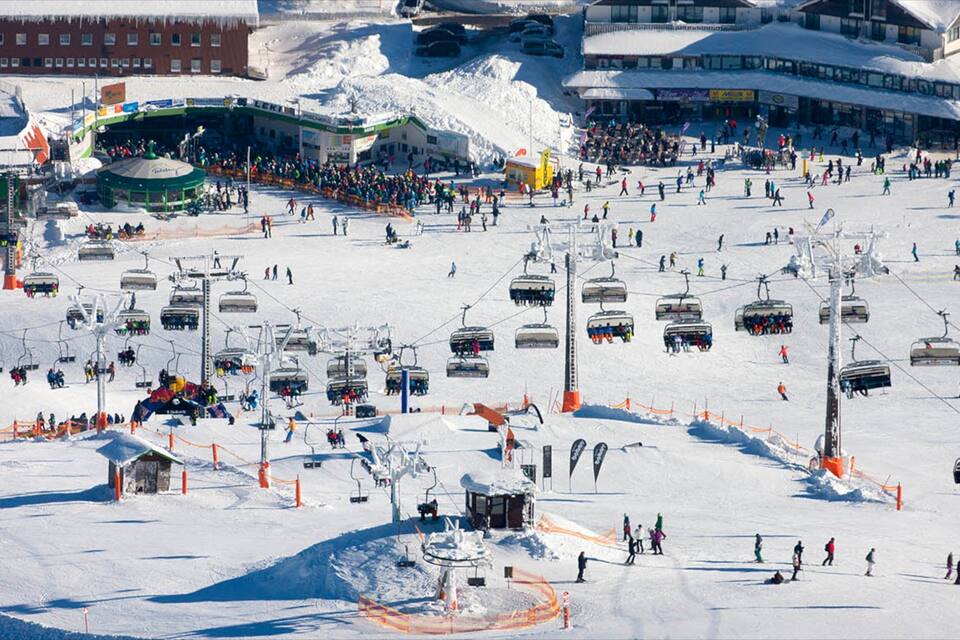 A snowy ski resort with multiple ski lifts, a ski area, and buildings in the background.