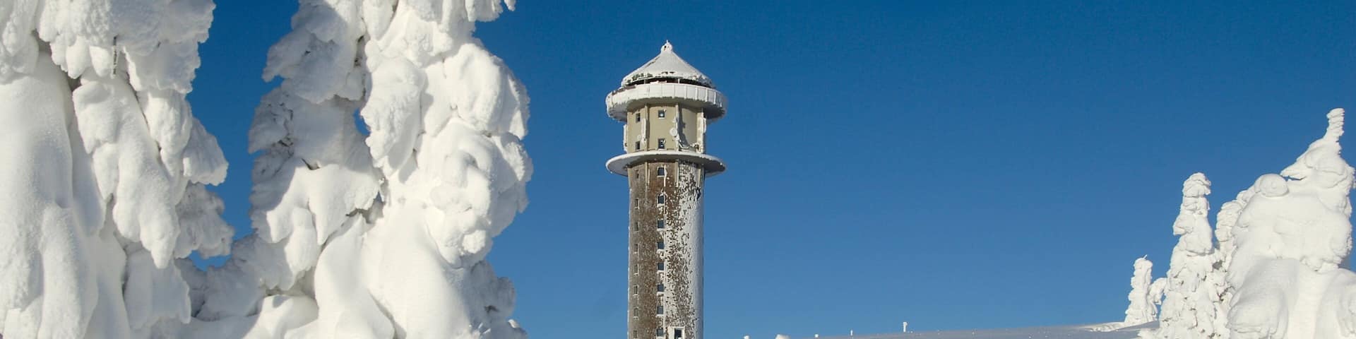 A snow-covered landscape with a lighthouse in the distance.