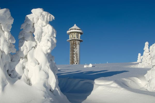 Schneebedeckte Landschaft mit einem Leuchtturm in der Ferne.