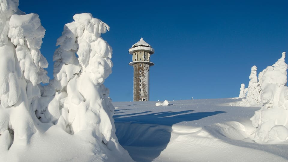 A snow-covered landscape with a lighthouse in the distance.
