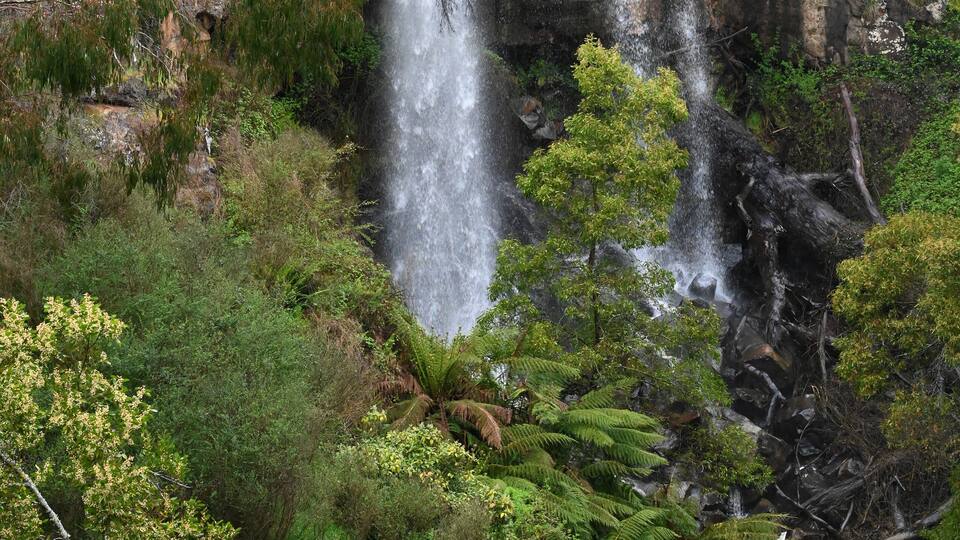 A waterfall cascading over rocky terrain surrounded by lush greenery.