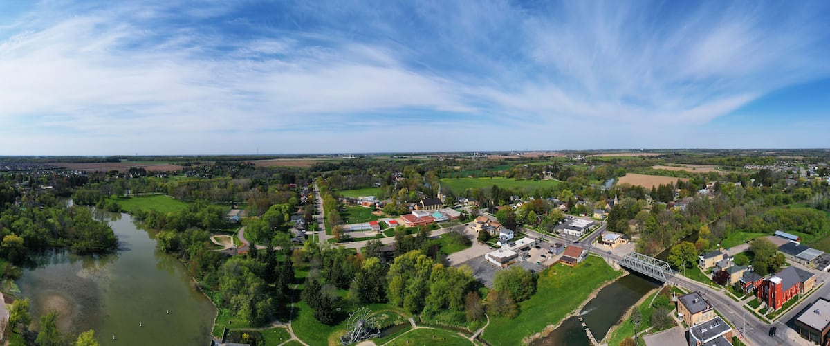 A town with a river, green fields, and a church.