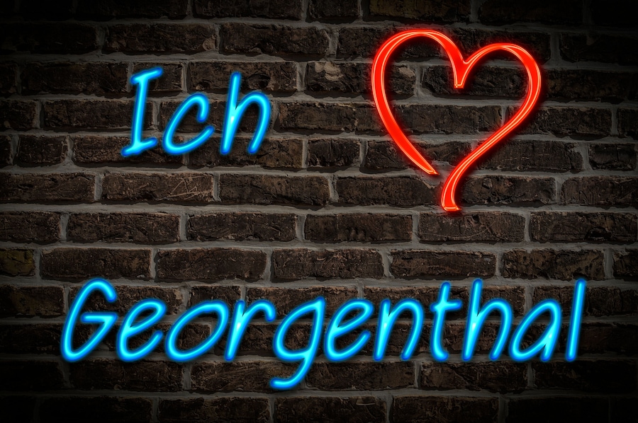 A brick wall with neon signs spelling "Ich Georgenthal" and a heart symbol.