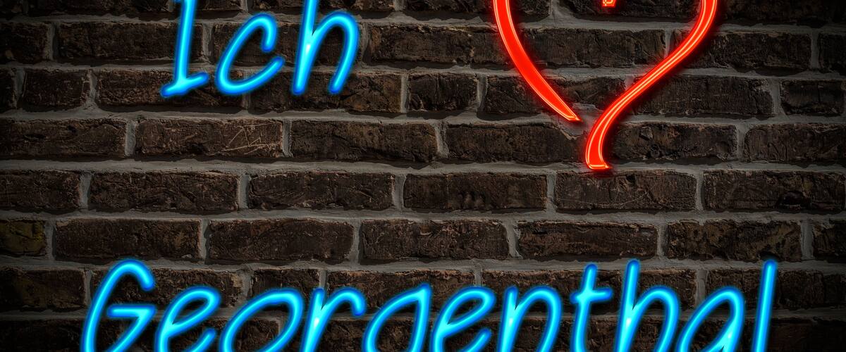 A brick wall with neon signs spelling "Ich Georgenthal" and a heart symbol.