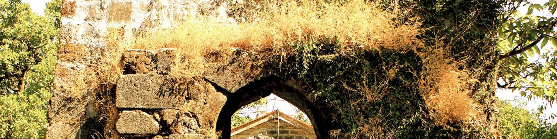 An ancient stone structure with a small arched doorway and steps leading up to it.
