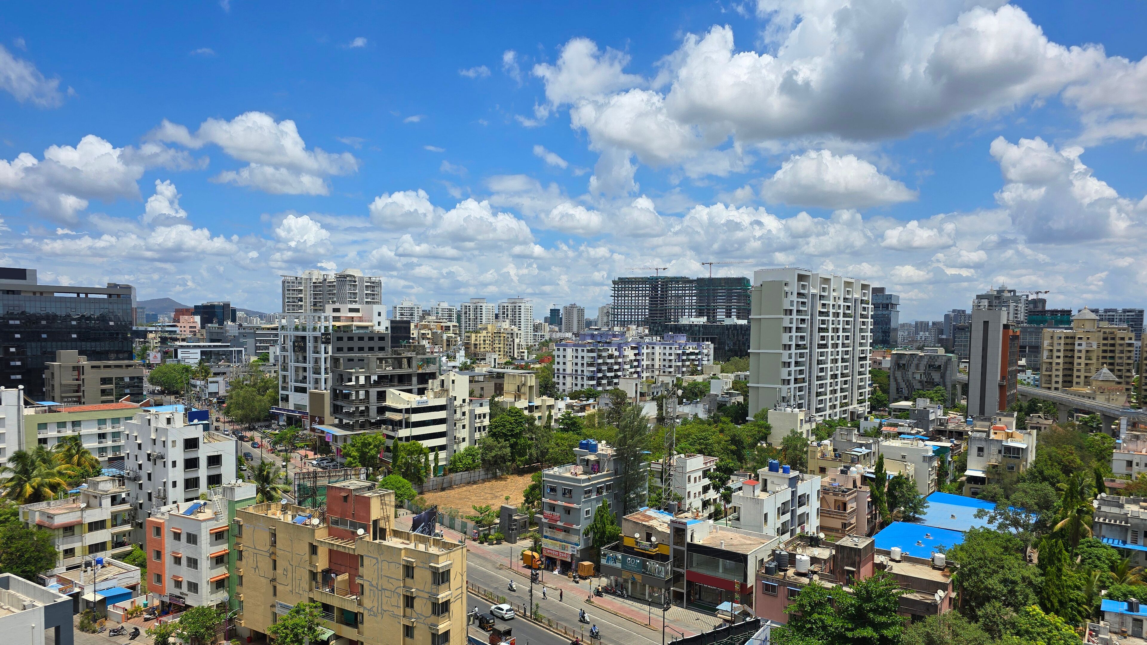 A cityscape with various buildings, including high-rises and mid-rise structures, under a partly cloudy sky.