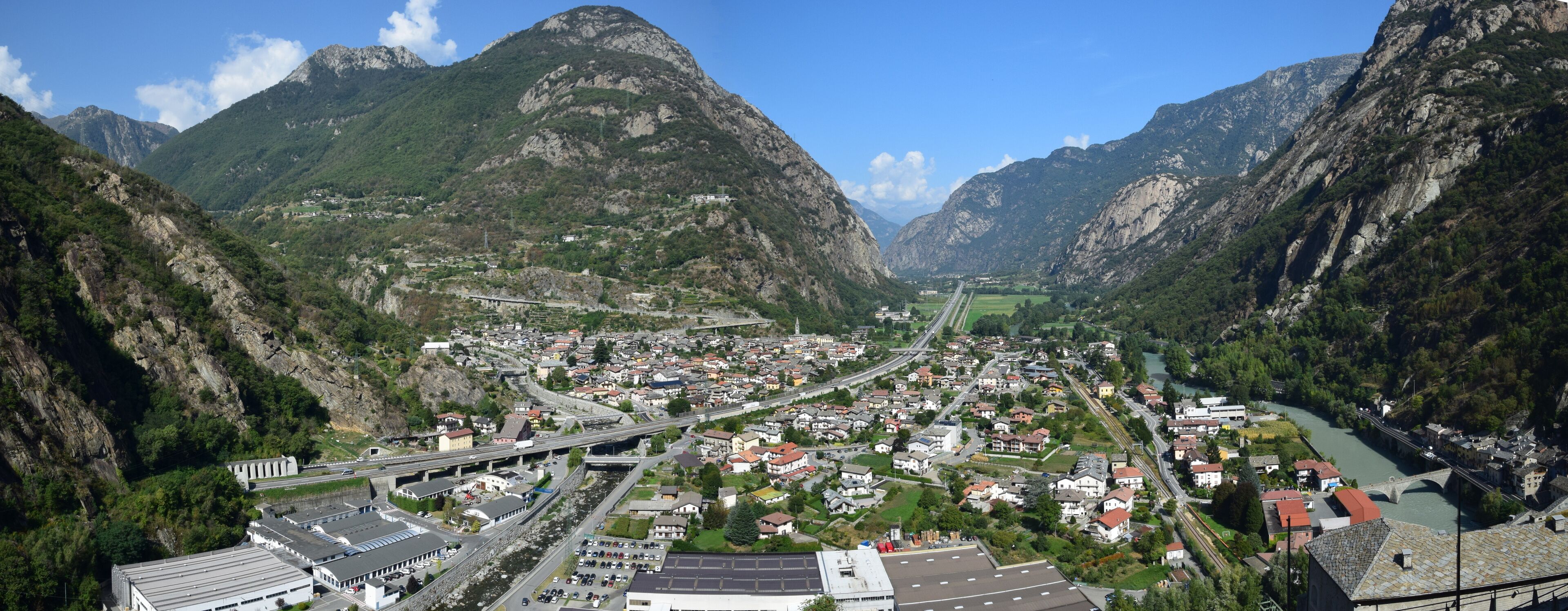 A valley with a river, a bridge, and a town surrounded by mountains.