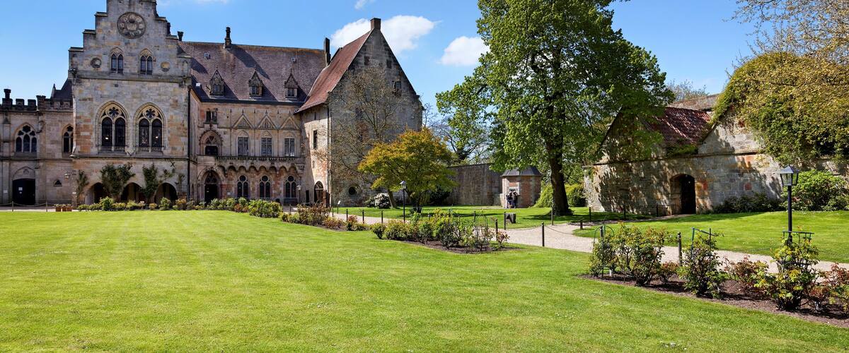 A historic building with a large lawn and a prominent tree in front.
