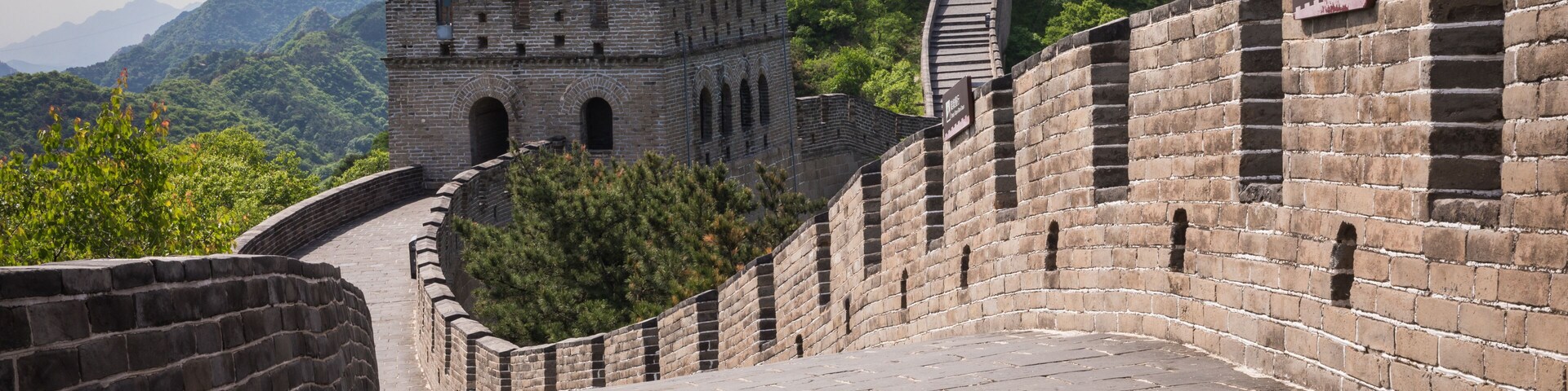 The Great Wall of China, a historic fortification, with traditional Chinese architecture and mountainous terrain in the background.