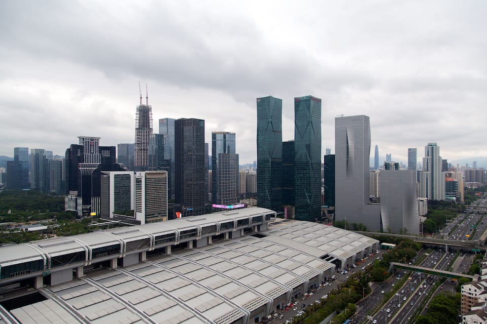 A cityscape with modern skyscrapers, a large train station, and a busy highway.