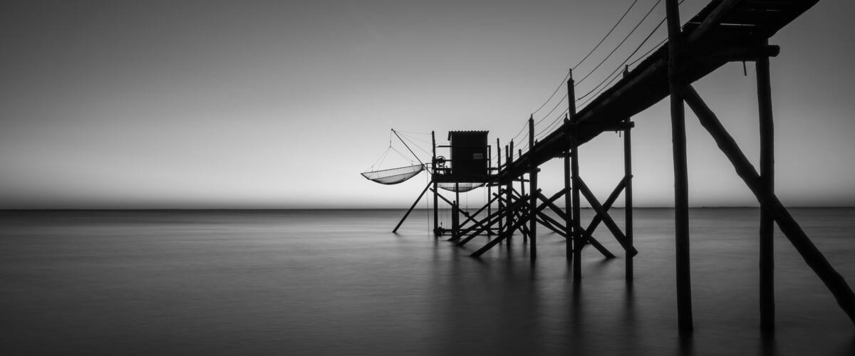 Traditional fishing hut with wooden walkway on the Atlantic coast at sunset, Aytre, France. black and white ppanorama shot