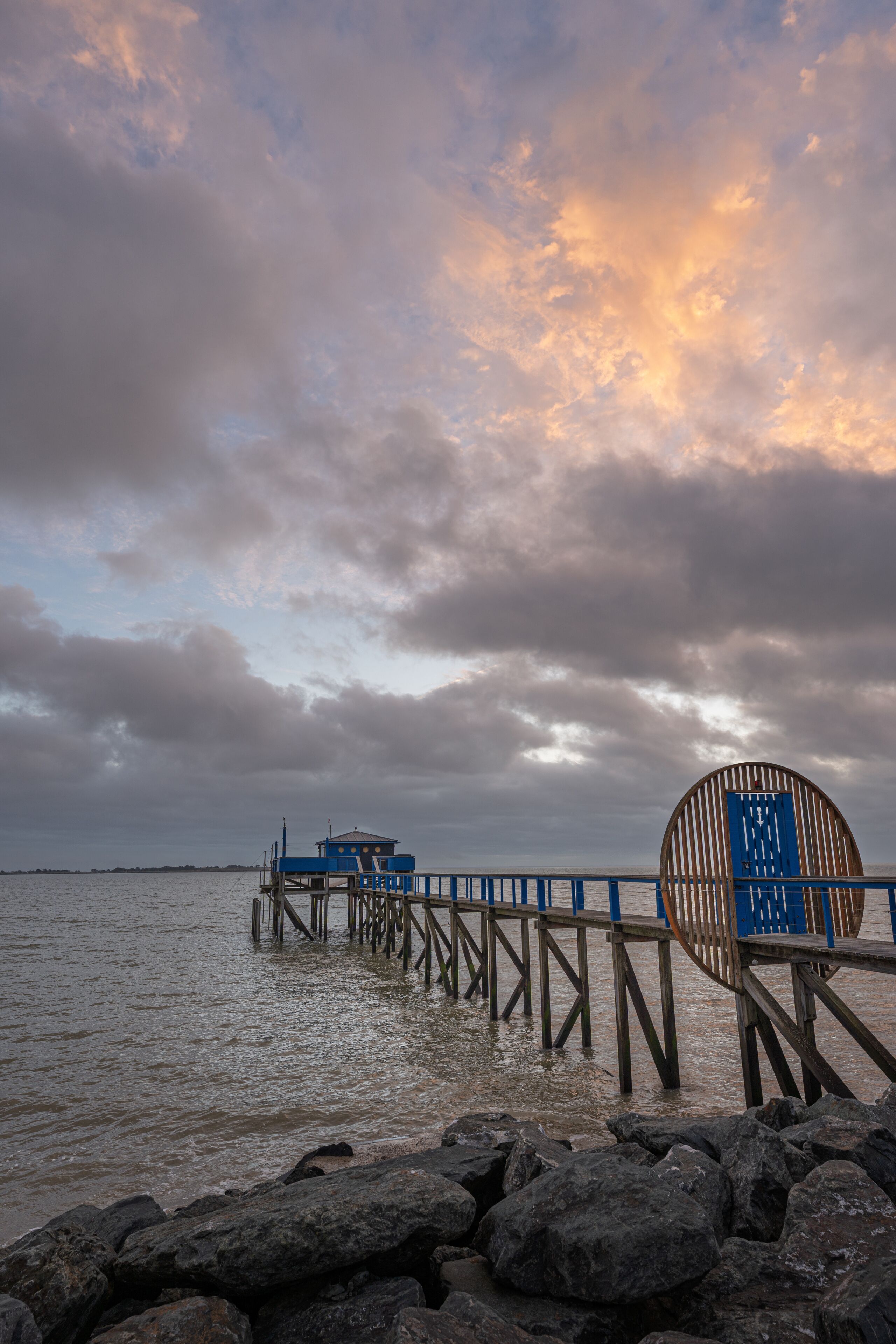 A pier extending into a body of water with a cloudy sky above.