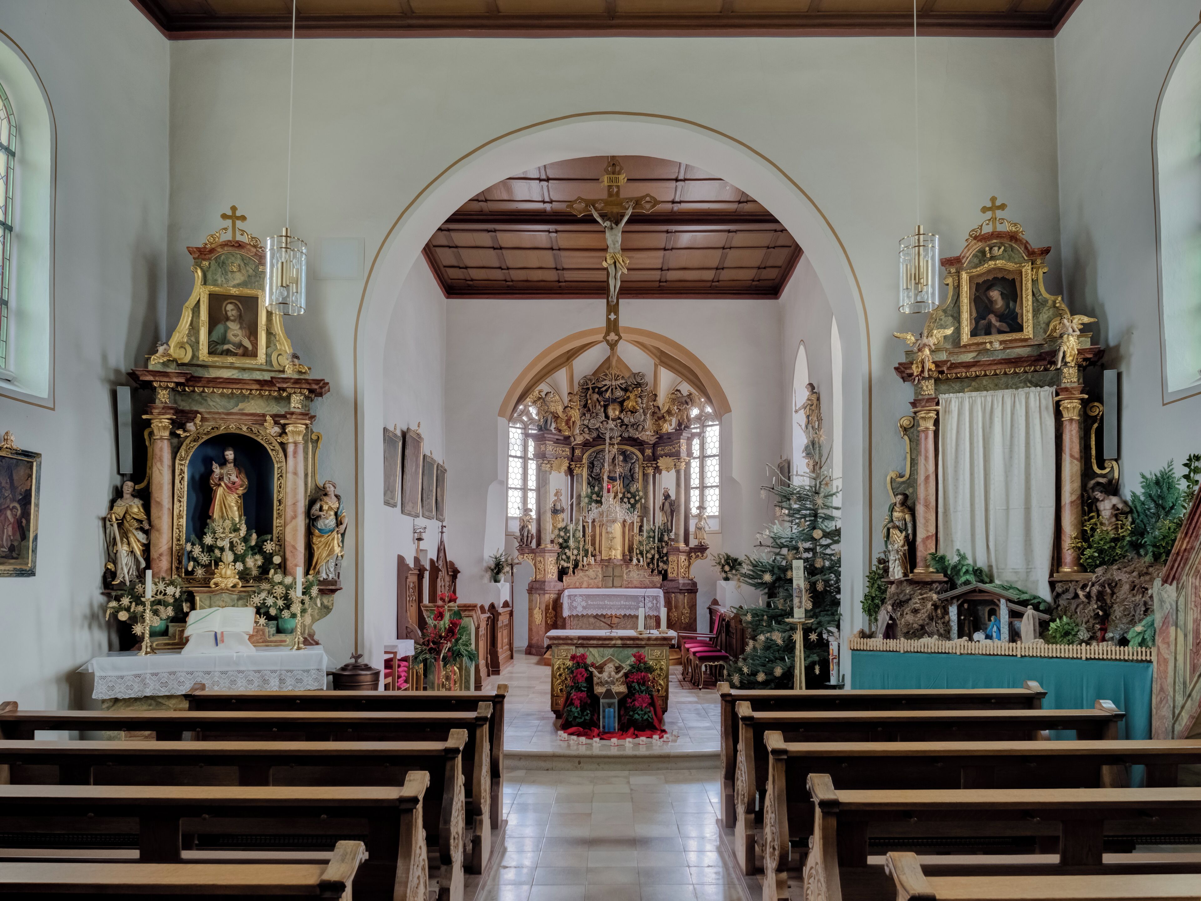 An ornate church interior with wooden pews, a crucifix, and religious statues.