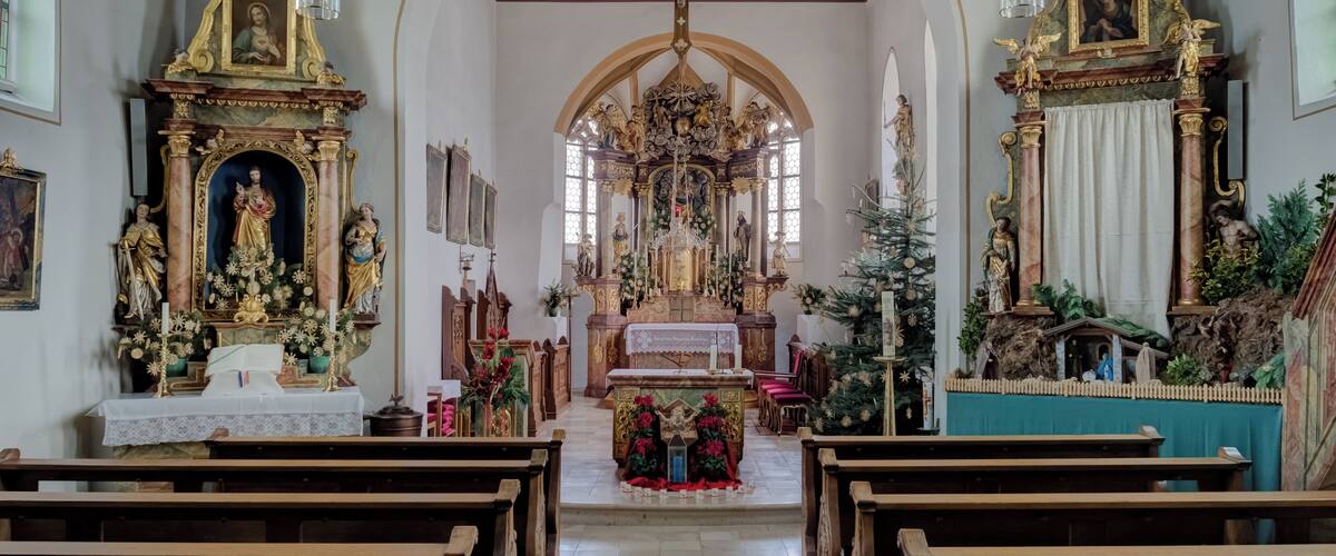 An ornate church interior with wooden pews, a crucifix, and religious statues.