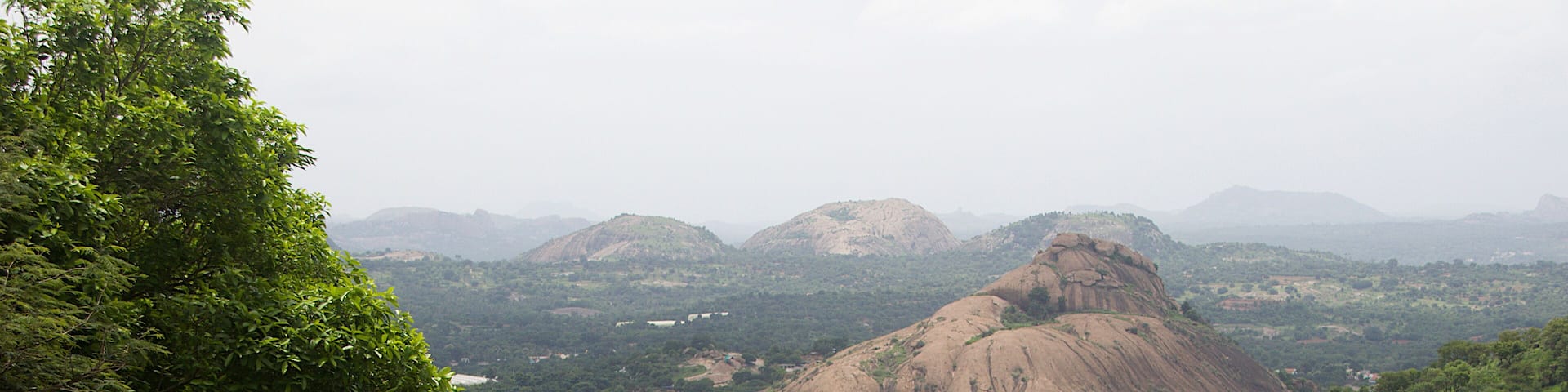 A mountainous landscape with a prominent rocky peak and lush greenery.