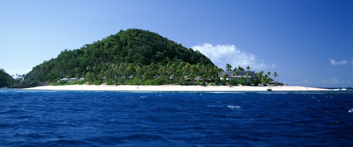 A tropical island with a beach and dense forest.