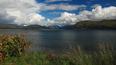 A lake with mountains in the background and a partly cloudy sky.