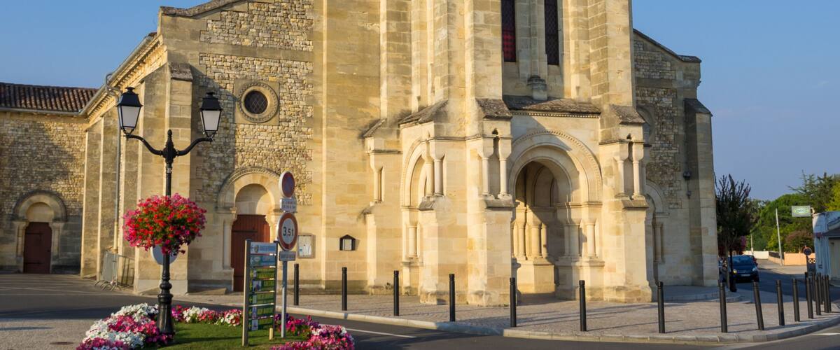 A historic church with a tall spire, arched windows, and a statue in front.