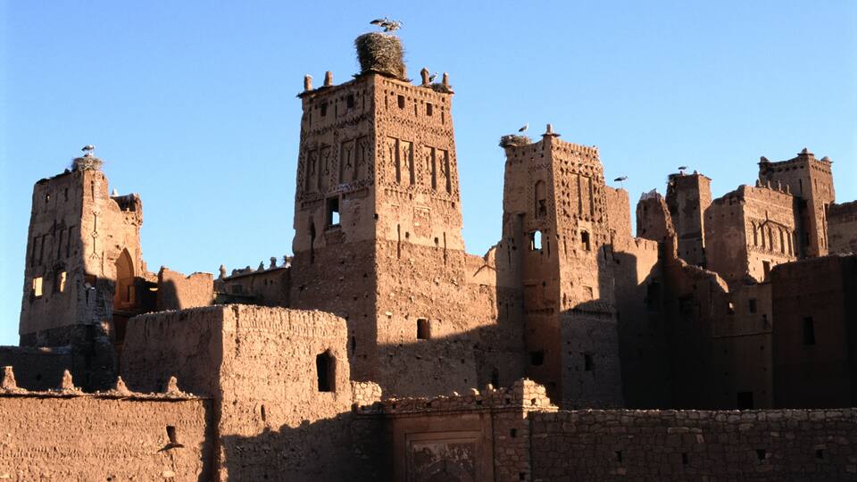 A historic fortress with multiple towers and walls, featuring intricate architectural details and a clear blue sky.