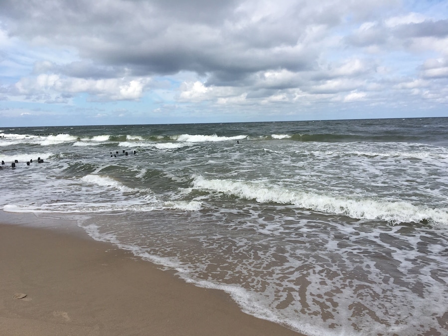 Uma praia com ondas quebrando na costa sob um céu nublado.
