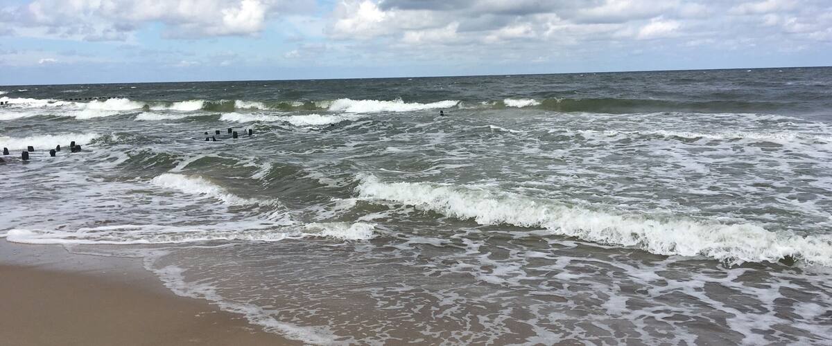 A beach with waves crashing onto the shore under a cloudy sky.