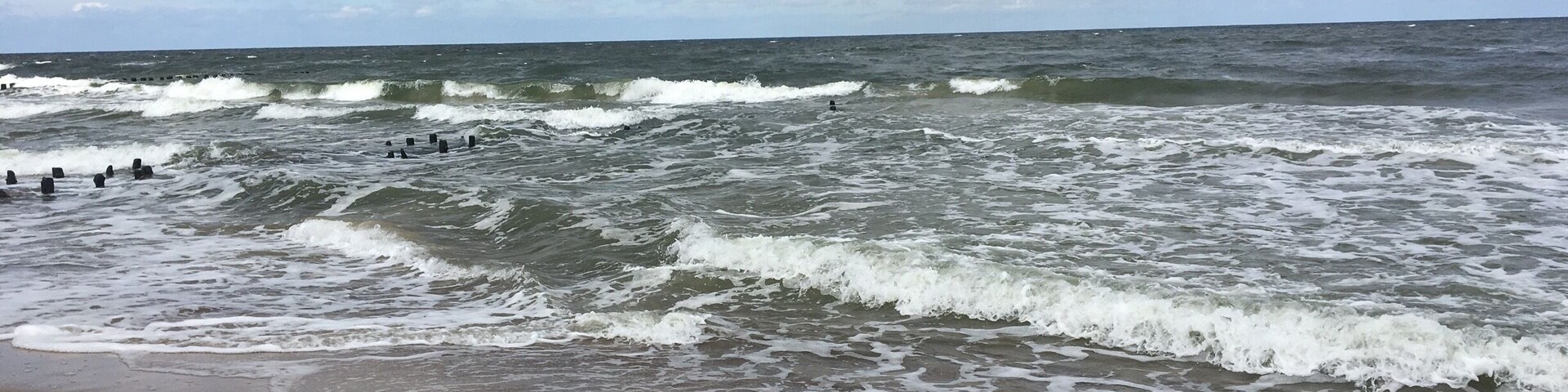 A beach with waves crashing onto the shore under a cloudy sky.