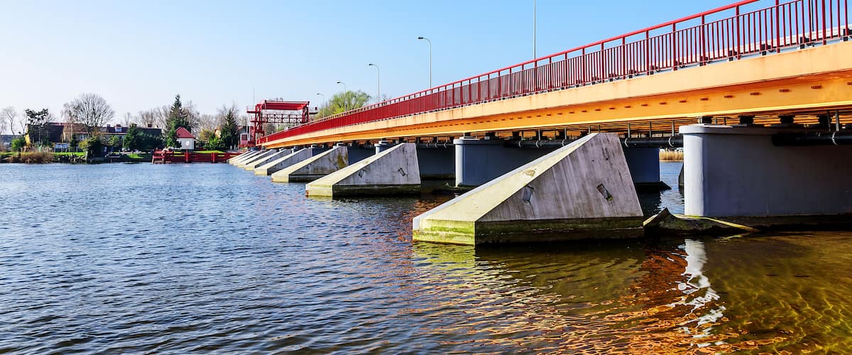 A bridge with red railings over a body of water.