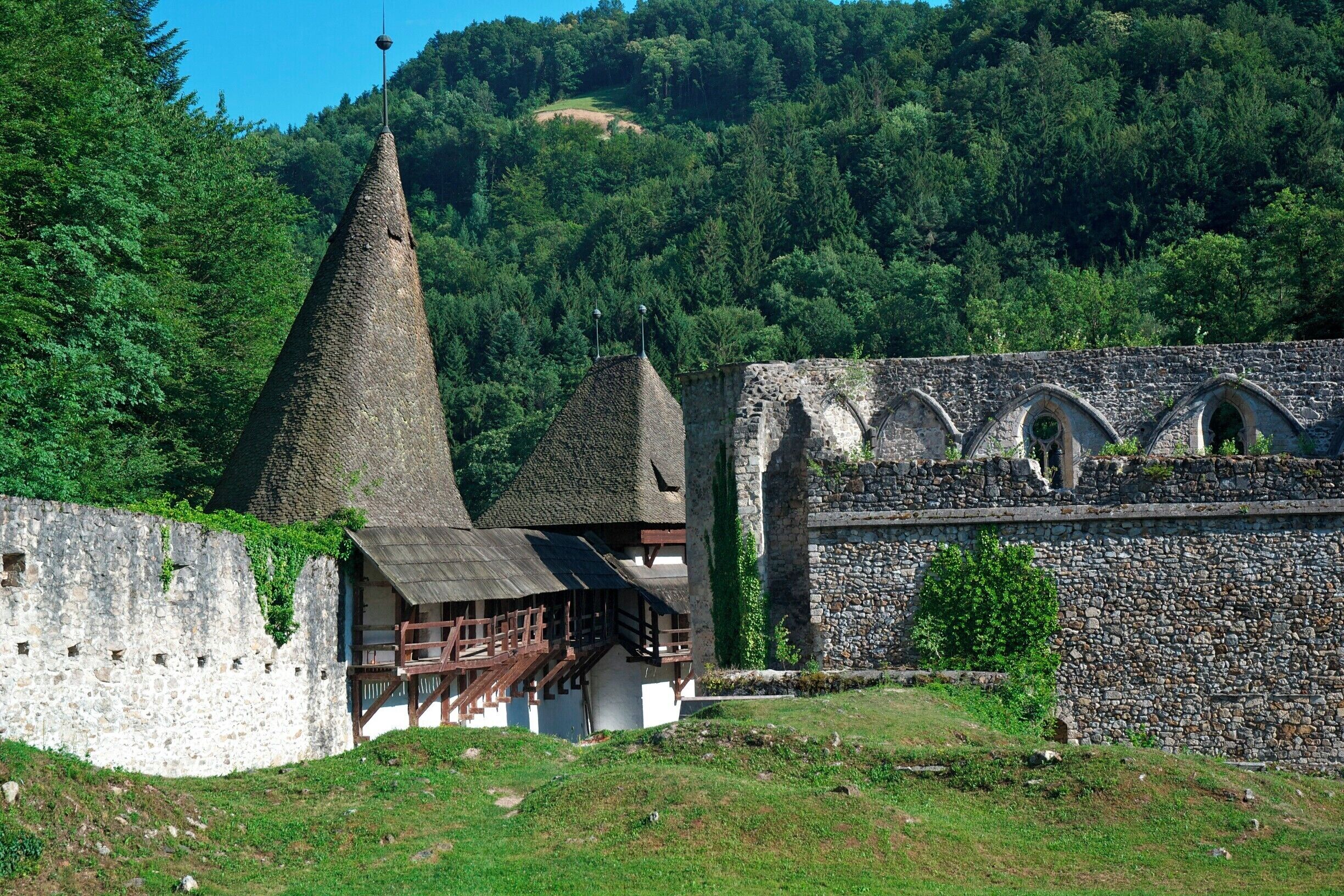 A historic stone building with a conical roof and a wooden structure with a balcony.