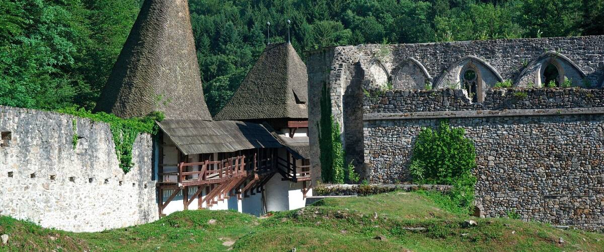 A historic stone building with a conical roof and a wooden structure with a balcony.
