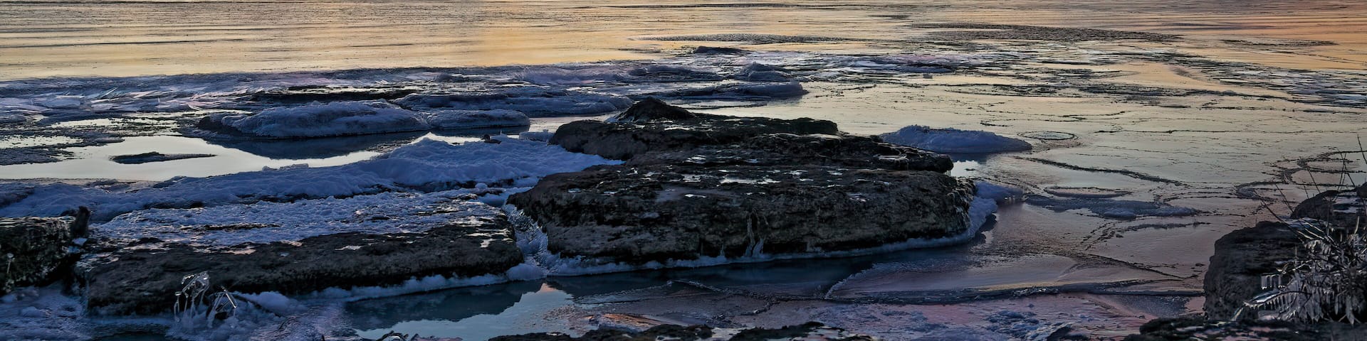 A frozen lake with ice formations and a sunset sky.