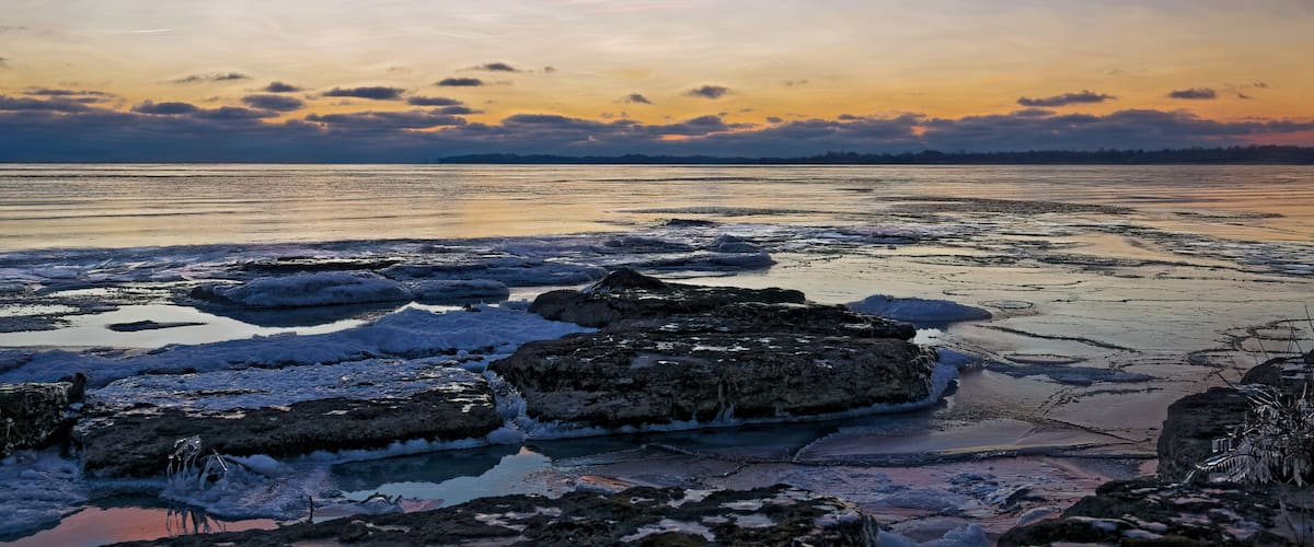 A frozen lake with ice formations and a sunset sky.