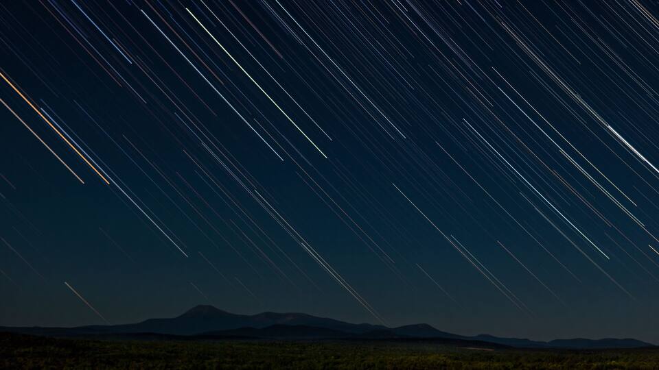 A starry night sky over a mountainous landscape.