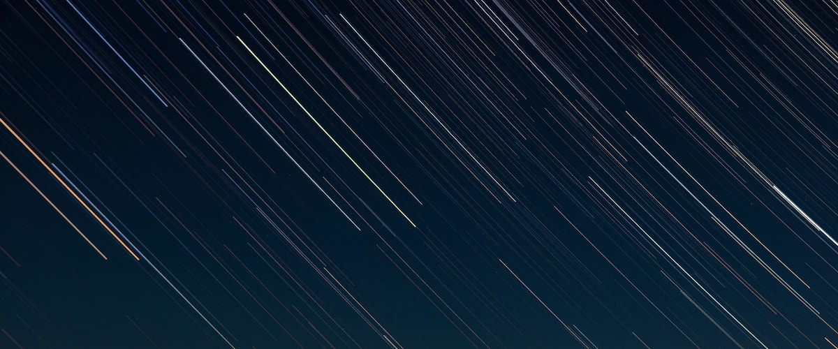 A starry night sky over a mountainous landscape.