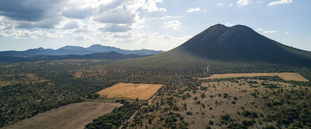 A mountain landscape with a clear sky and scattered clouds.
