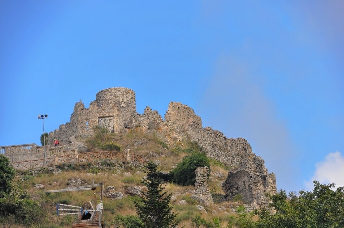 A historic stone castle ruin on a hill with a clear sky.