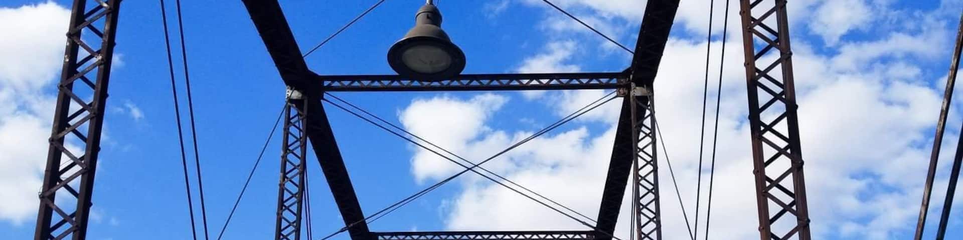 A steel bridge with a bell in the center, under a clear blue sky.