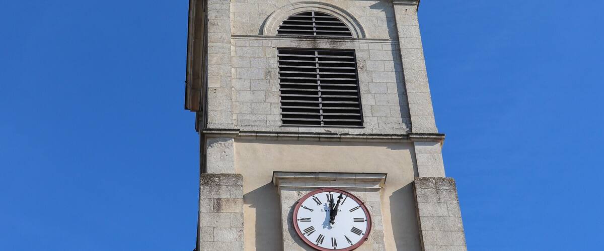 A church tower with a clock and a weather vane.