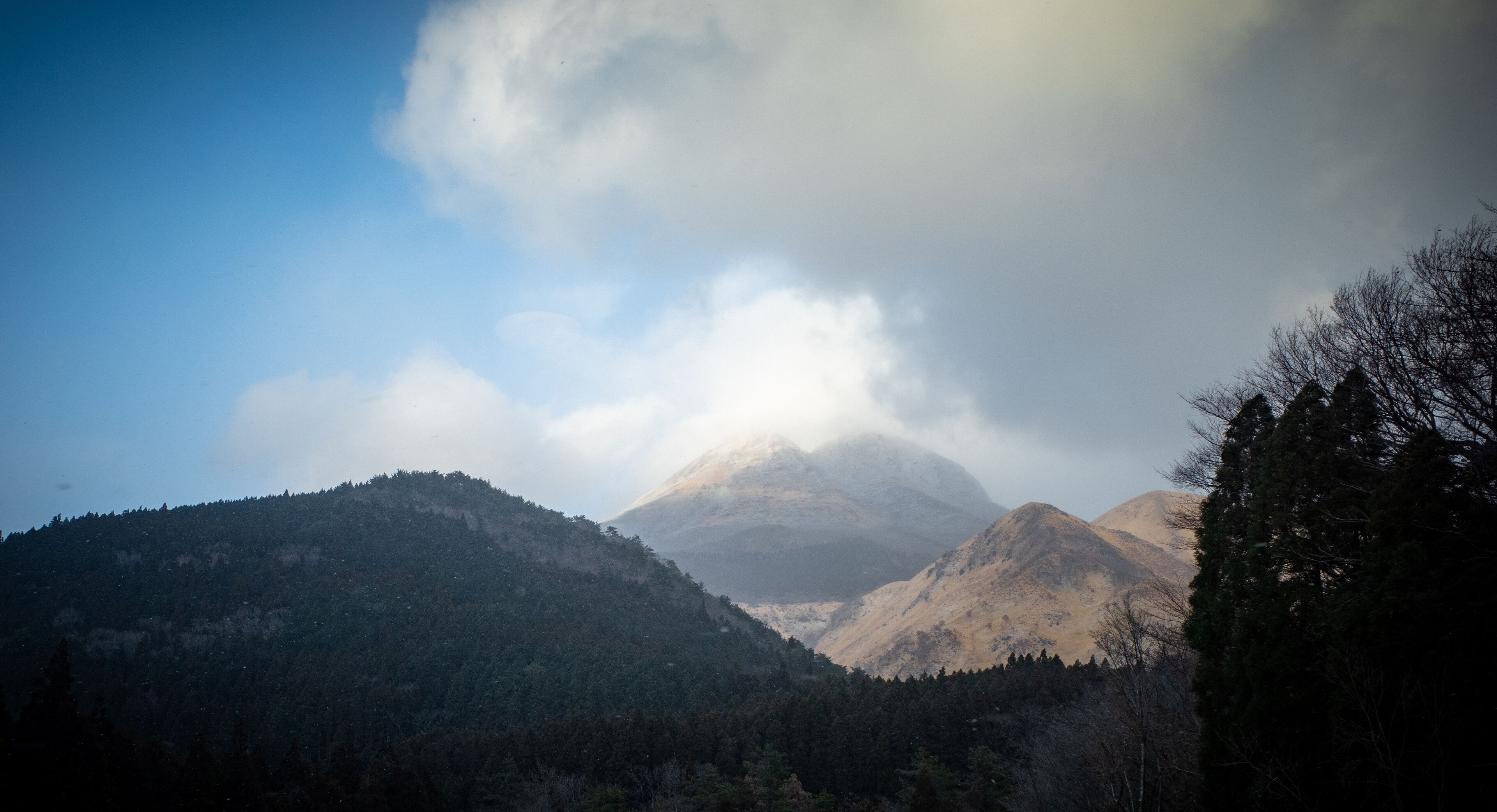 A mountain range with a prominent peak partially obscured by clouds.