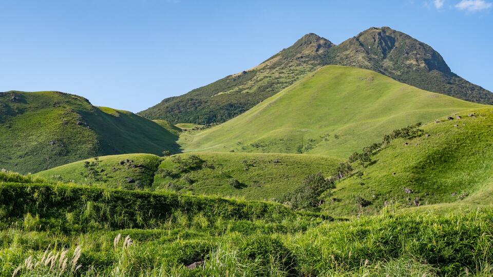 A mountainous landscape with lush green hills and a prominent peak.