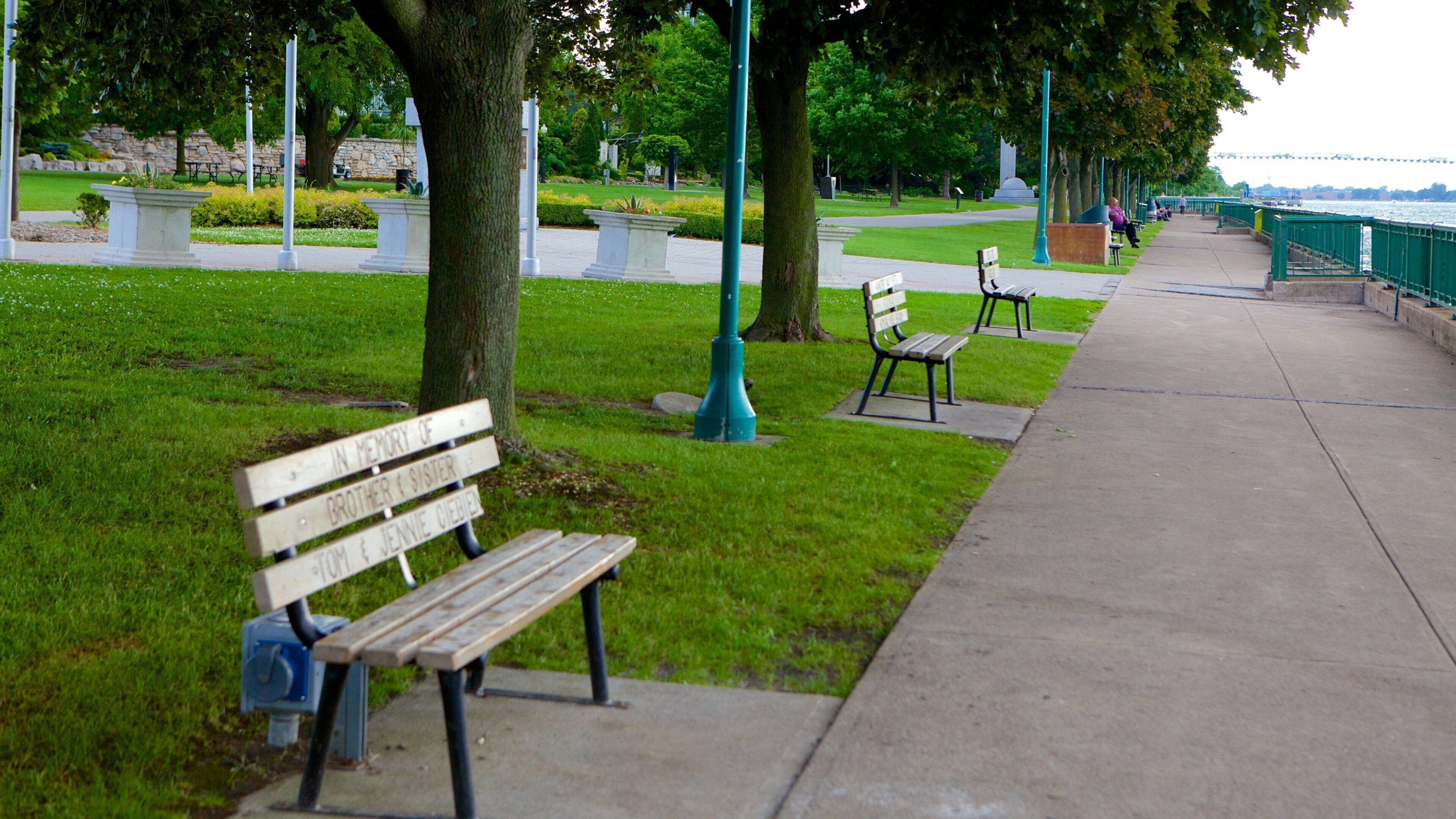 A park with benches, a pathway, and a river.