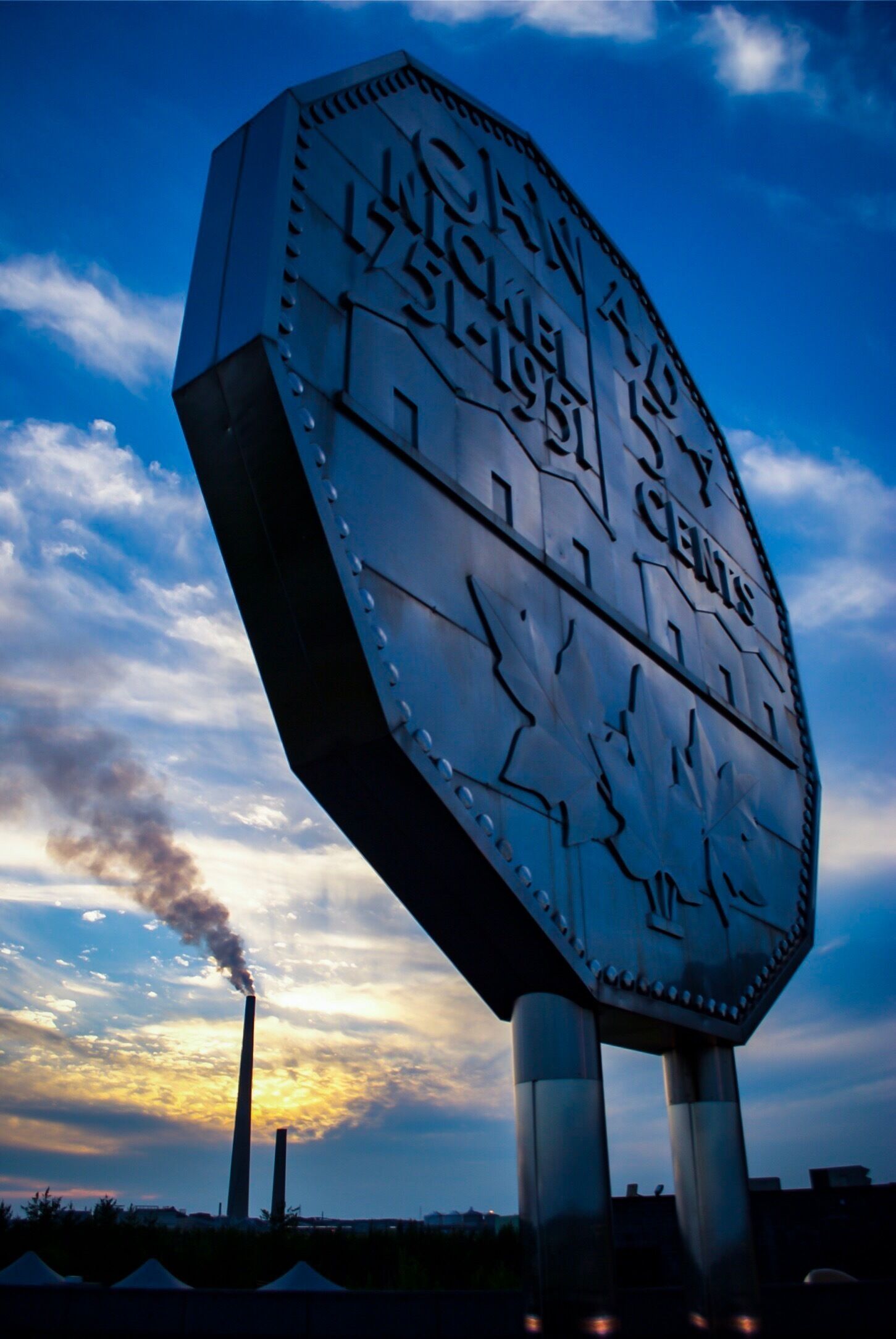 A large, metallic sign with the text "CLEAN ENERGY" against a sunset sky.