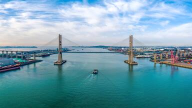 Manho-ri, Pyeongtaek-si, Gyeonggi-do, South Korea - November 27, 2022: Aerial view of tugboat and cargo ship sailing on the sea against Seohae Bridge besides Pyeongtaek Port