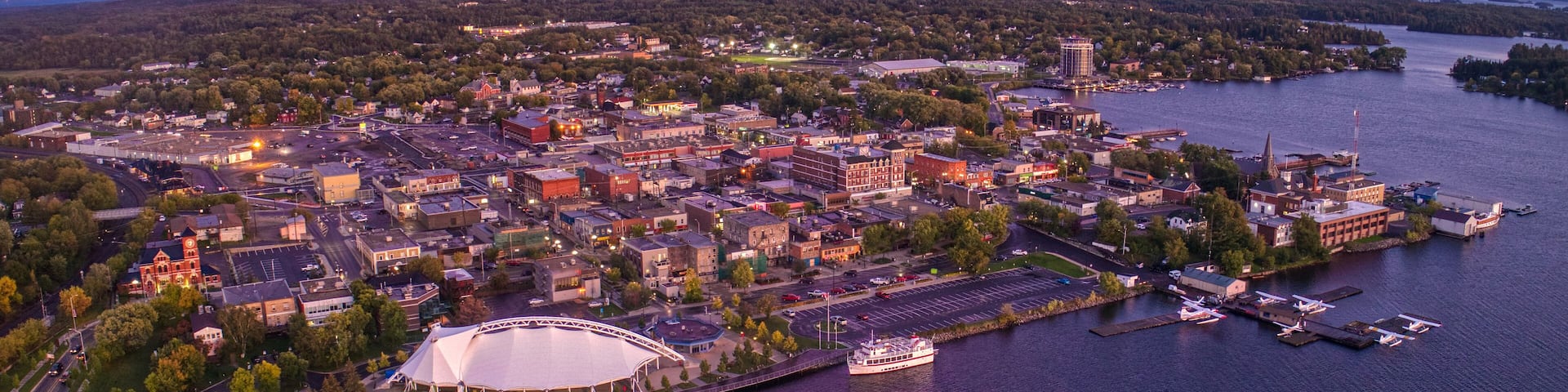An aerial view of a city with a large stadium, a marina, and a river.