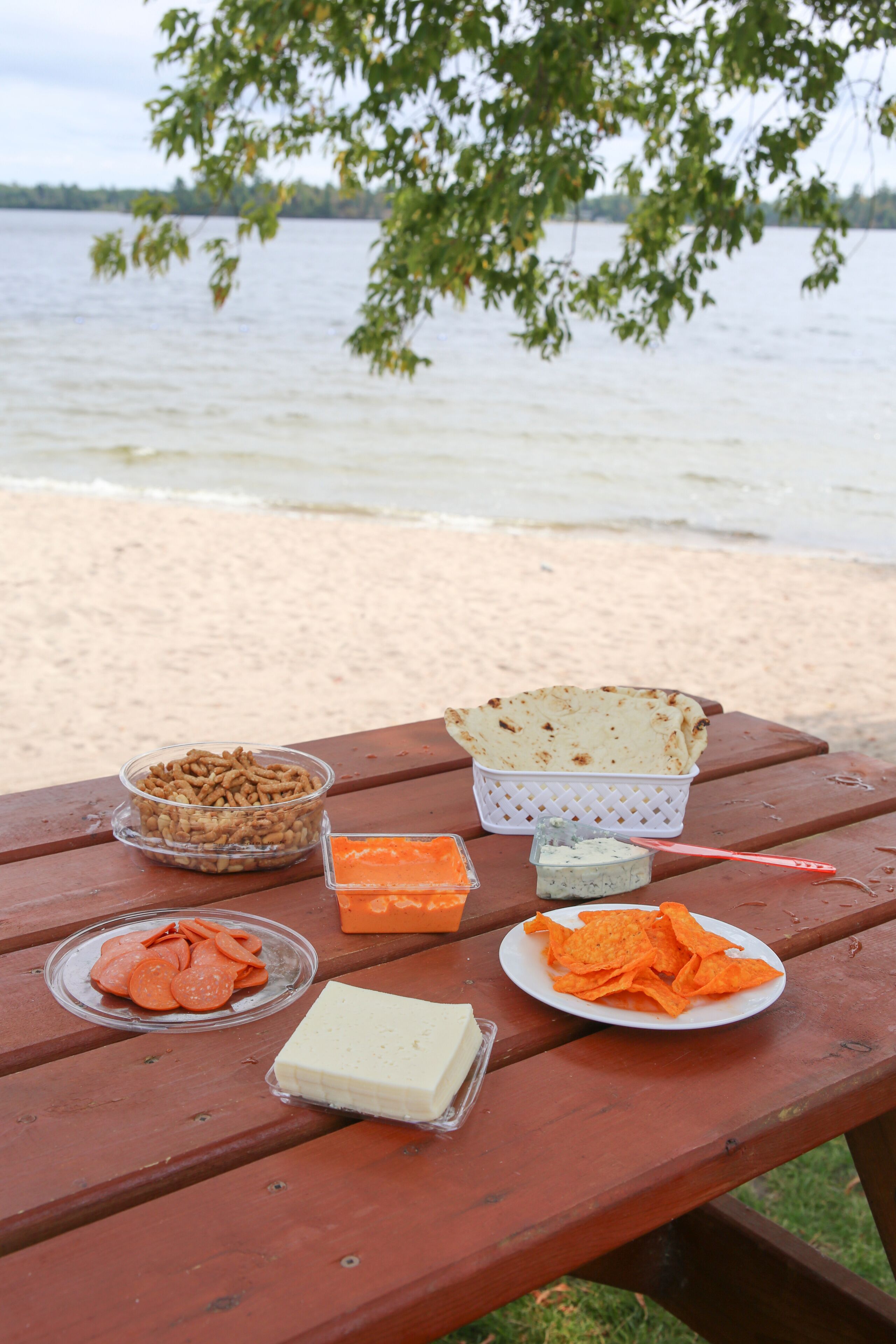 Una mesa de picnic con aperitivos y vistas al lago.