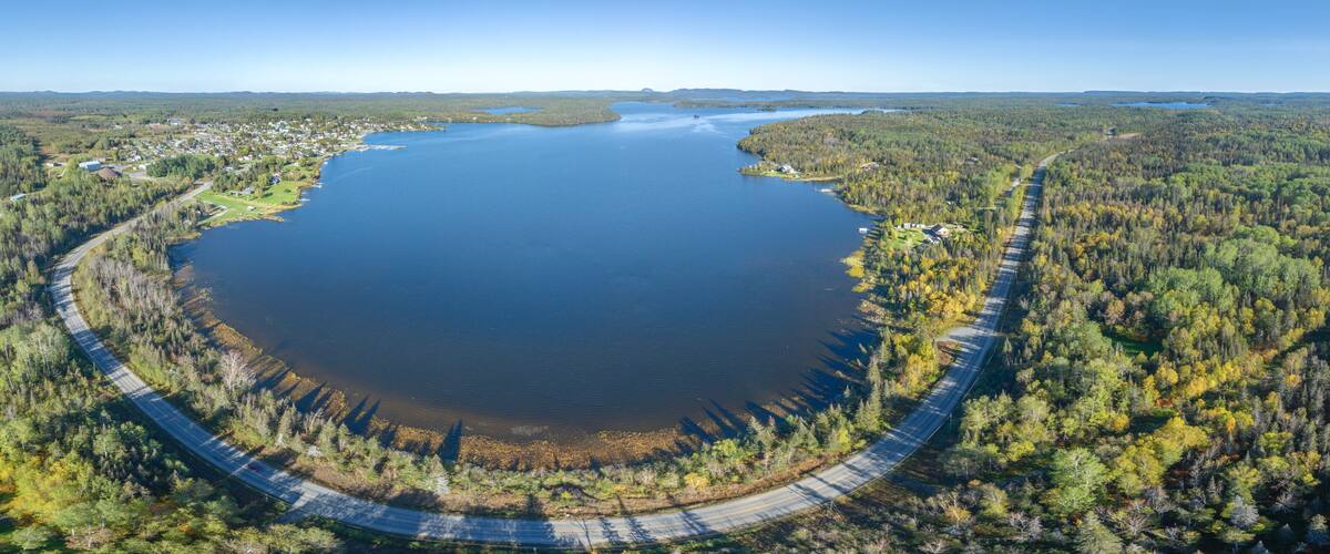 A large lake surrounded by dense forests and a winding road.