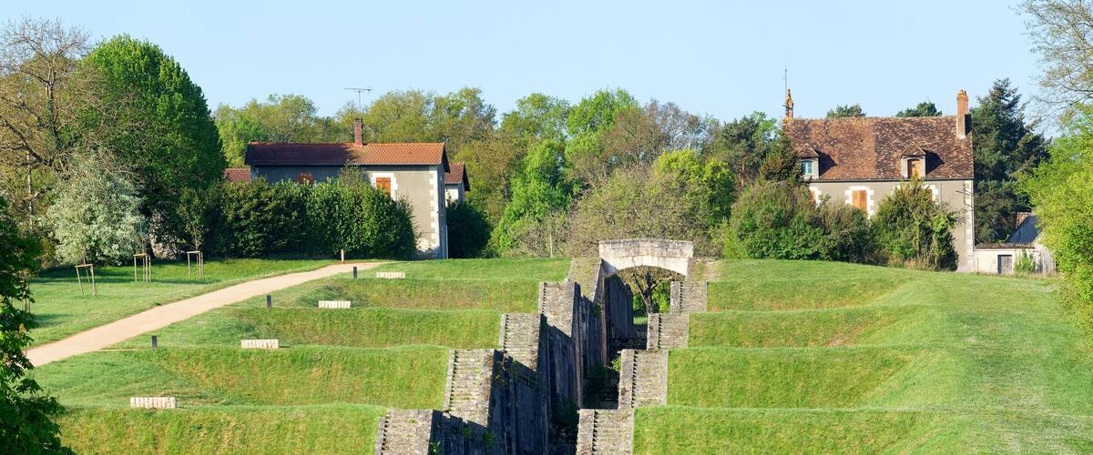 A historical stone structure with a pathway leading to a house.